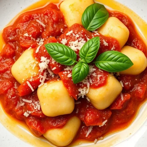 Italian gnocchi with vibrant red tomato sauce, fresh basil leaves, grated parmesan cheese, golden olive oil drizzle, rustic p
